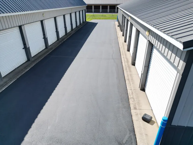 Aerial view straight down a drive aisle lined with numbered storage unit doors on both sides