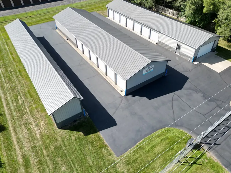 Aerial view of three long storage buildings with white roll-up doors and paved aisles between them