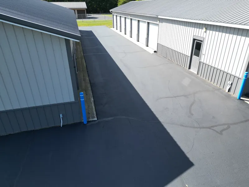 A wide paved aisle between two storage buildings, with the office door marked 101 on the right