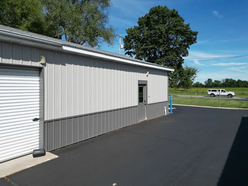 The office building entrance marked 101 beside a roll-up door, with the road and open fields behind