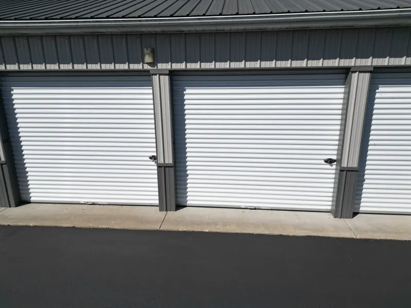 A clean white roll-up door on a storage unit, lit by the exterior light under the building eave