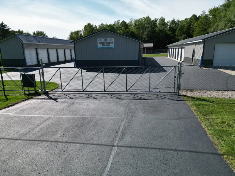 A closed sliding security gate with the storage buildings and keypad beyond it
