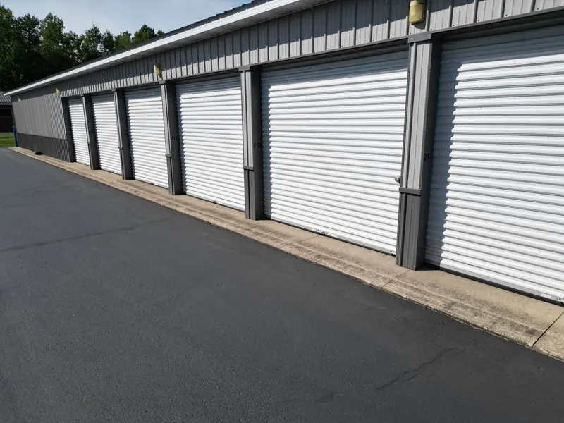Numbered storage units 211 through 216 with white roll-up doors along a paved aisle
