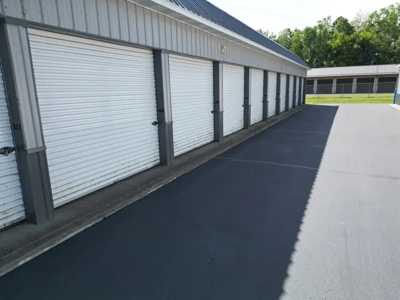 Storage units 301 through 308 with white roll-up doors along a freshly sealed asphalt aisle
