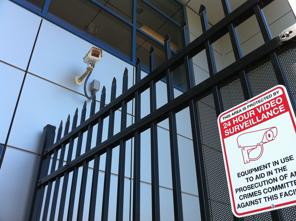 A security camera and steel gate protecting a self storage facility under 24-hour video surveillance